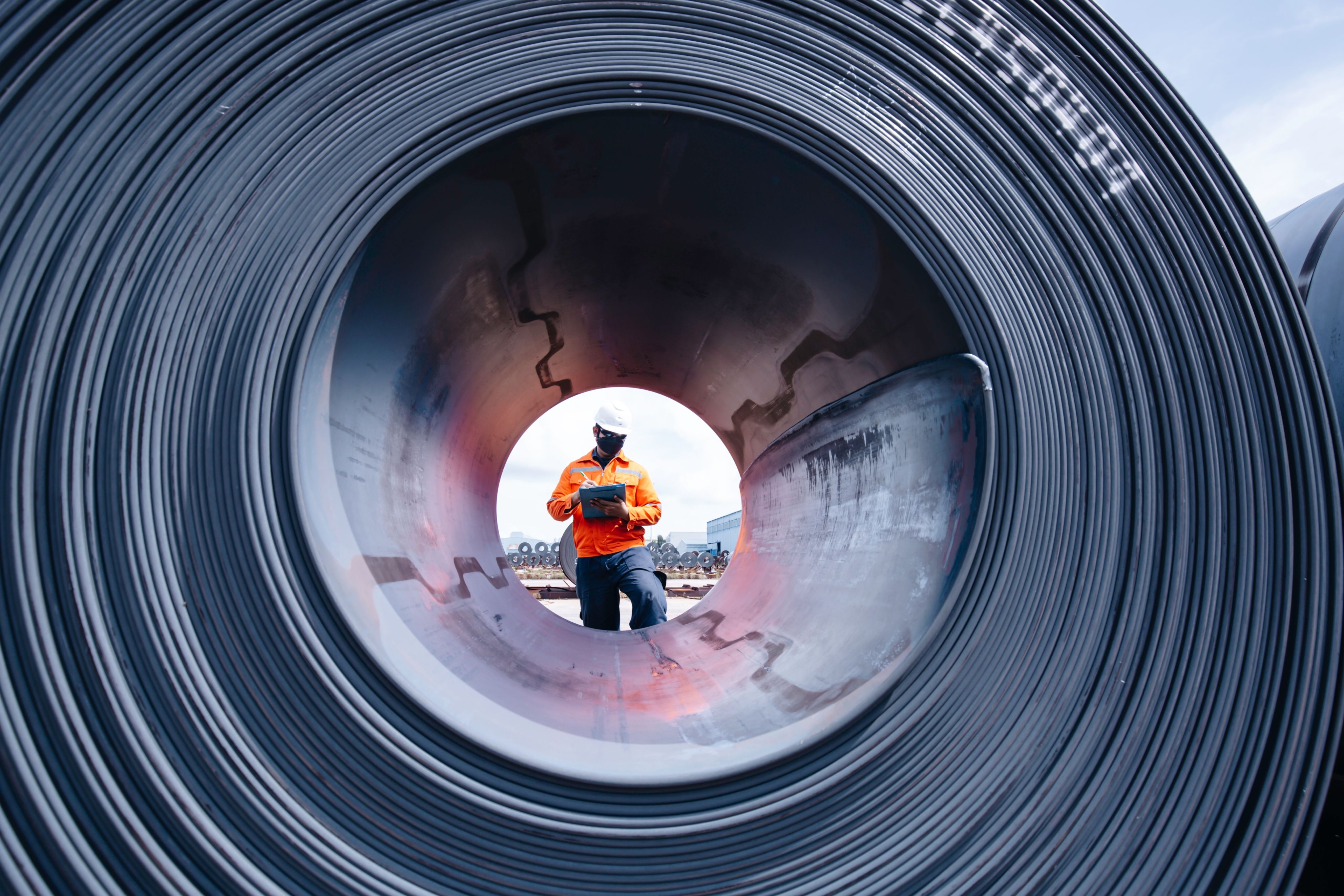 A man inspects a steel coil.